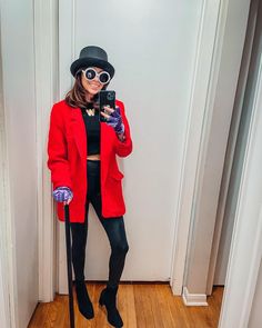 a woman in a red coat and hat taking a selfie