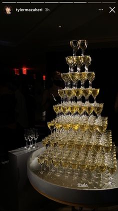 a very tall stack of wine glasses sitting on top of a table in a room