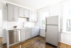 an empty kitchen with white cabinets and stainless steel appliances, including a dishwasher