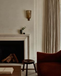 a living room with a fire place, chair and table in front of a window