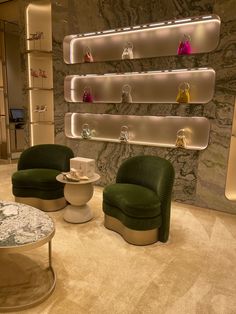 a living room with two green chairs and a coffee table in front of a marble wall