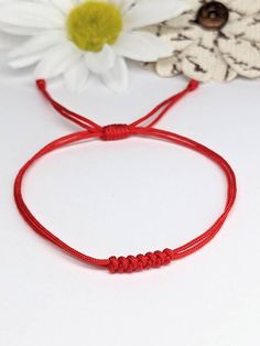 the red string bracelet is next to a flower