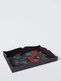 a black tray with flowers painted on the front and bottom, sitting on a white surface