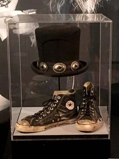 a pair of sneakers in a display case with an empty top hat on the bottom