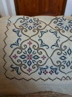 an embroidered pillow on top of a wooden chair