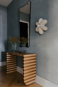 a wooden table with vases on it in front of a mirror and wall decoration