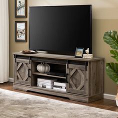 a flat screen tv sitting on top of a wooden entertainment center in a living room