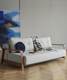 a white couch sitting on top of a hard wood floor next to a blue painting