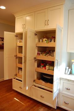 an open pantry door in a kitchen with wooden floors and white cabinets on both sides