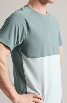 a man is holding his stomach while wearing a t - shirt with an asymmetrical design