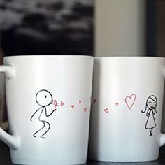 two white coffee mugs with stick figures on them sitting on a table next to each other