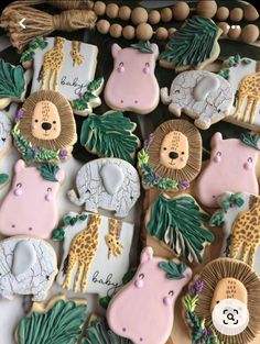 decorated cookies with jungle animals and giraffes are displayed on a table next to tassels