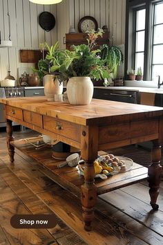 a wooden table sitting in the middle of a kitchen next to a potted plant