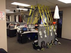 an office cubicle with many items on the desk and ladders hanging from the ceiling