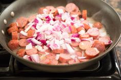 hot dogs and onions cooking in a pan on the stove