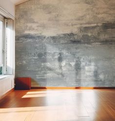 an empty room with wood flooring and a large painting on the wall behind it