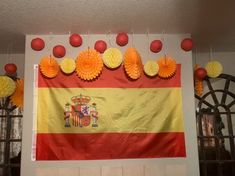 a flag hanging on the wall next to some paper balls and tissue pom poms