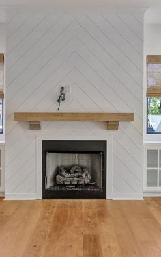 an empty living room with white walls and wood flooring on the wooden floors, along with a fireplace