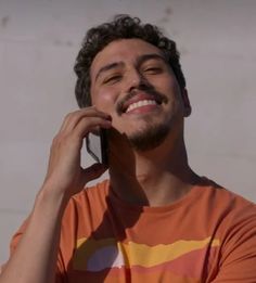 a man talking on a cell phone while wearing an orange and yellow t - shirt