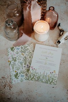 the wedding stationery is laid out on the floor next to candles and other items