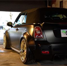 the rear end of a black car parked in a garage