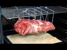 a raw piece of meat is being cooked in an oven with a wire rack over it