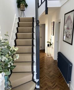 there is a vase with flowers sitting on the stair case next to the stairs in this house