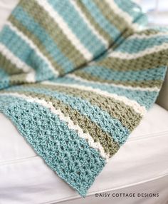 a crocheted blanket sitting on top of a white couch next to a pillow