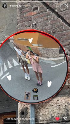 a mirror that is on the side of a pole with a reflection of two people in it