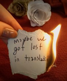 a person holding a piece of paper with writing on it and a candle in front of them