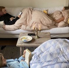 two people laying on a couch with books and candles in front of them as they look at each other