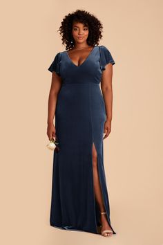 a woman in a long blue dress with a slit down the side and her hand on her hip