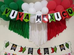 some balloons and streamers are hanging from the ceiling in front of a mexican flag banner