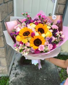 a bouquet of sunflowers and pink carnations in front of a door