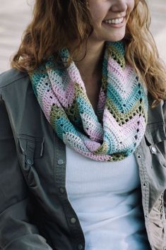 a smiling woman wearing a multicolored knitted scarf