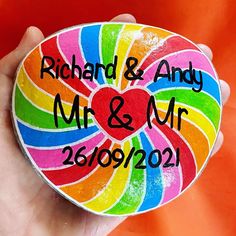 a hand holding a colorful candy heart with the words mr and mrs in black on it