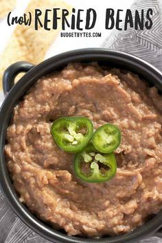 a black bowl filled with refried beans and jalapeno peppers on top