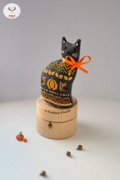 a cat figurine sitting on top of a wooden box with an orange ribbon