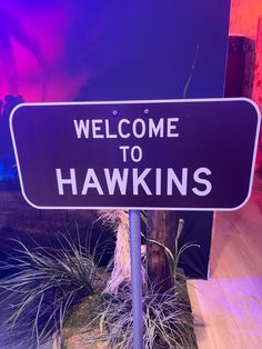 a sign that says welcome to hawkins in front of a purple and blue background