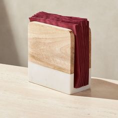 a wooden block with red napkins sitting on it's side next to a white box