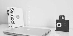 an open laptop computer sitting on top of a white desk next to a black and white box