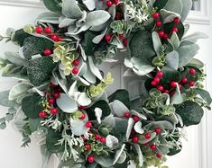 a wreath with red berries and greenery hanging on the front door's side