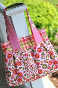 a handbag hanging from the side of a white fence post with flowers on it