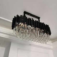 a chandelier hanging from the ceiling in a room with white walls and black trim