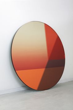 an orange and brown circular object sitting on top of a white floor next to a wall