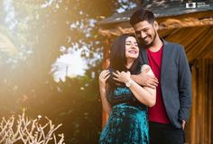 a man and woman standing next to each other in front of a tree with the sun shining on them