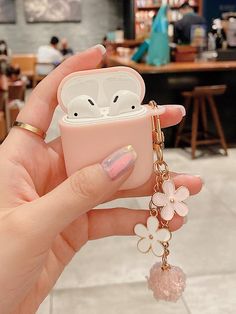 a hand holding a pink case with an animal keychain hanging from it's side