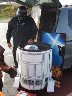 a man in a darth vader costume standing next to a giant trash can