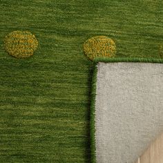 a green area rug with two yellow circles on the top and one white circle at the bottom