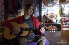 a woman sitting in a chair holding a guitar